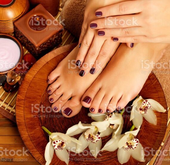 Closeup photo of a female feet at spa salon on pedicure procedure. Female legs in water decoration  the flowers.